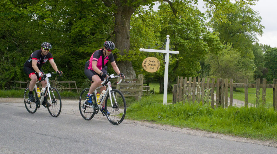 Two cyclists riding past the south ormsby hall sign.