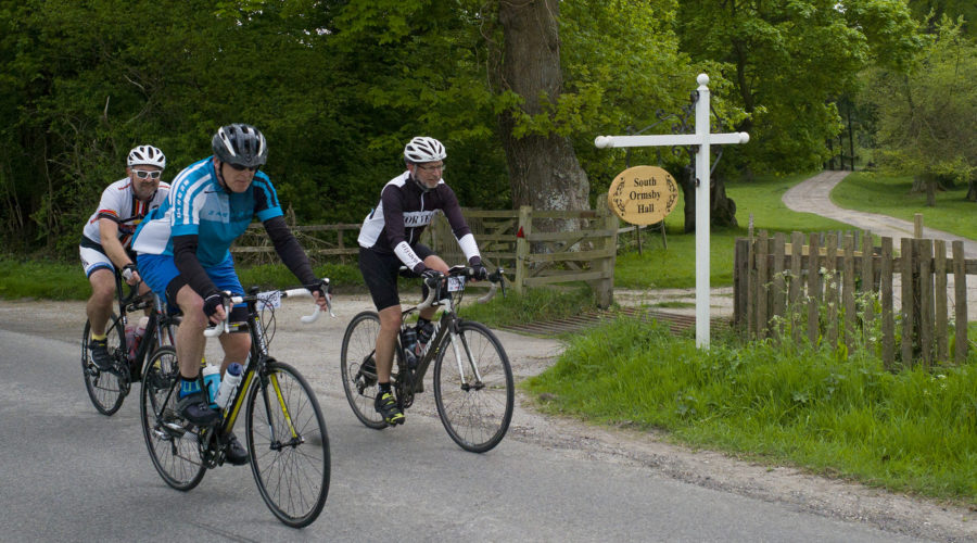 Three cyclists riding past the south ormsby hall sign