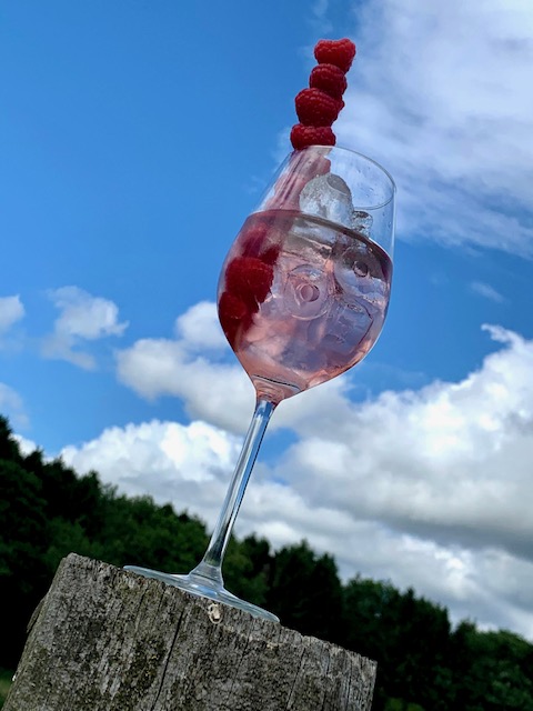 Pink gin in a glass with raspberries