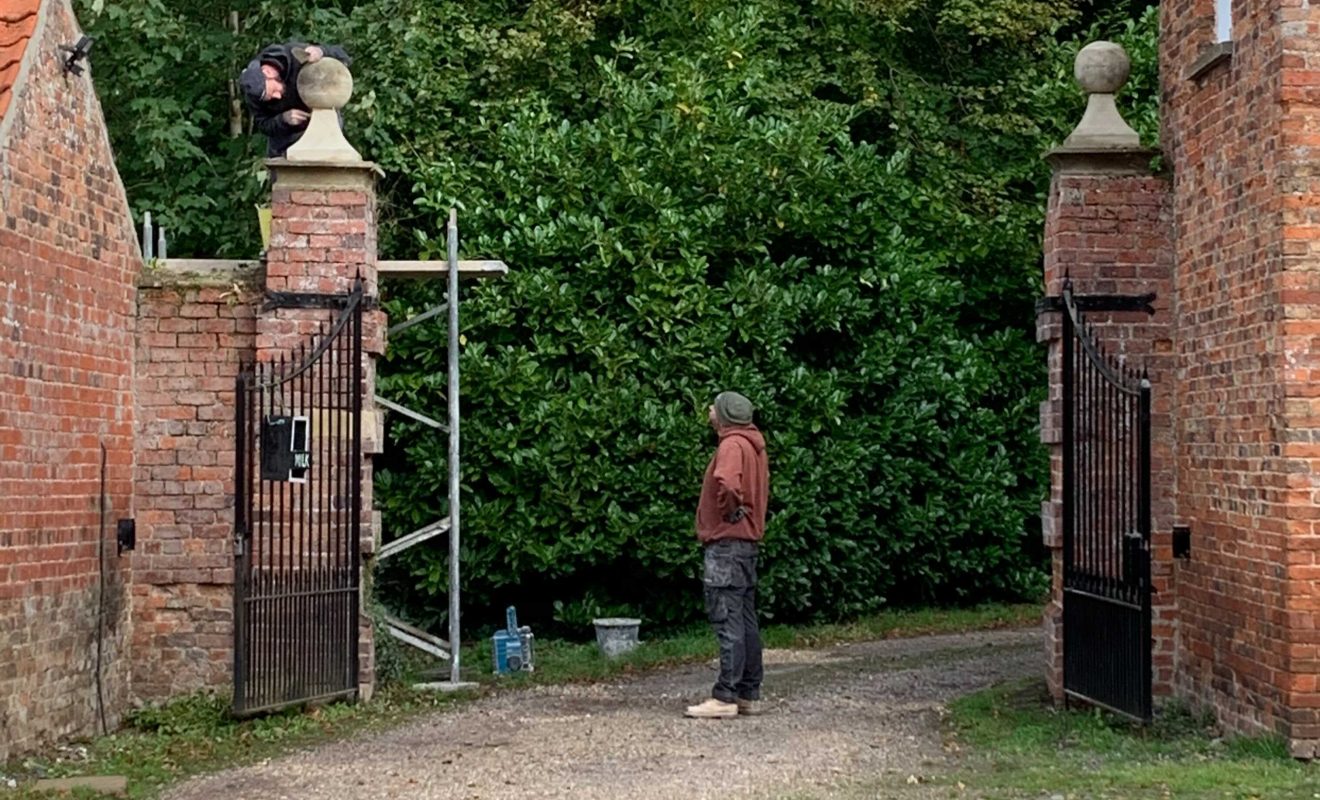 Two men resorting a stone ball that had fallen from the Estate wall